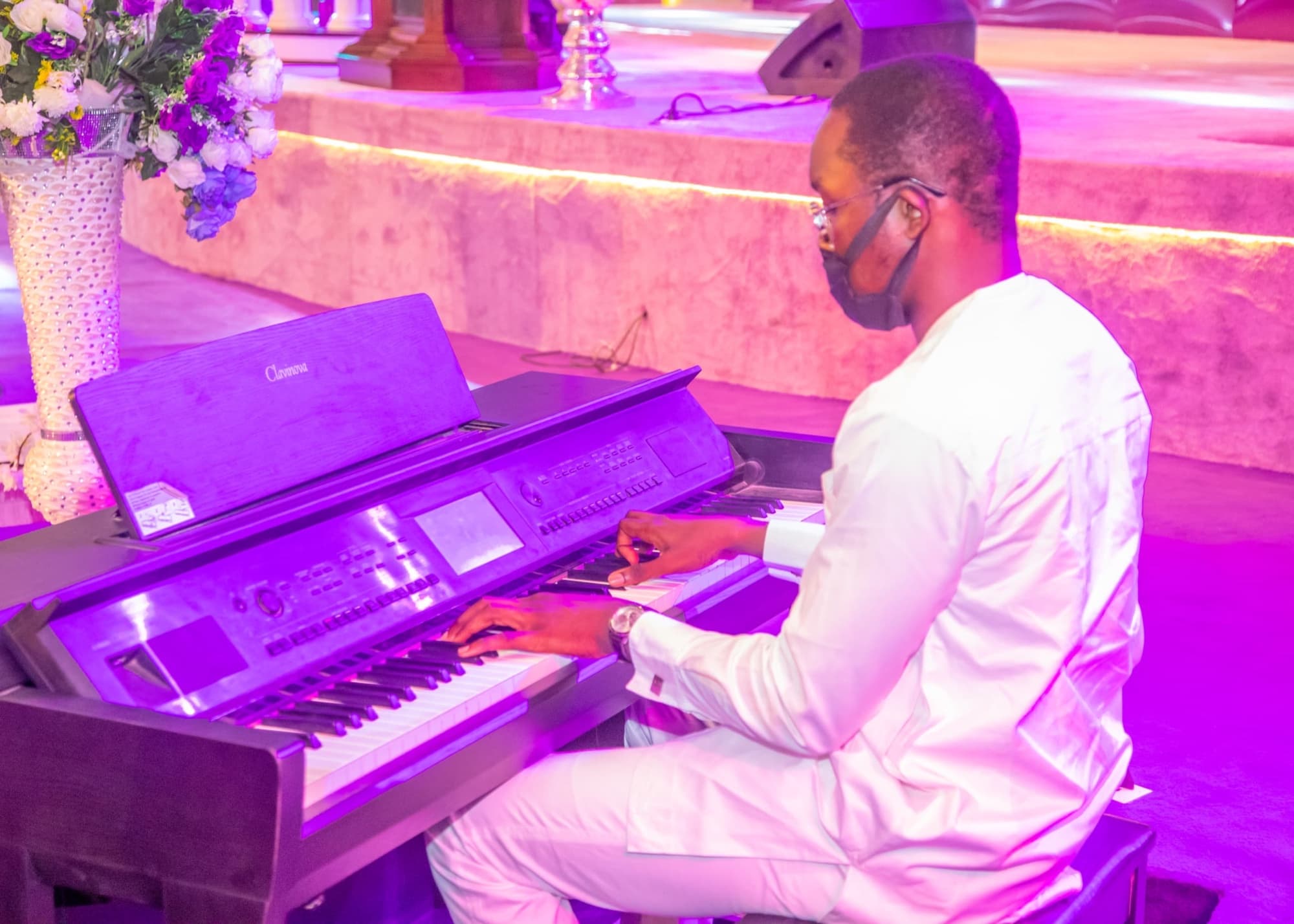 Oladimeji at a Clavinova piano under pink and violet stage light